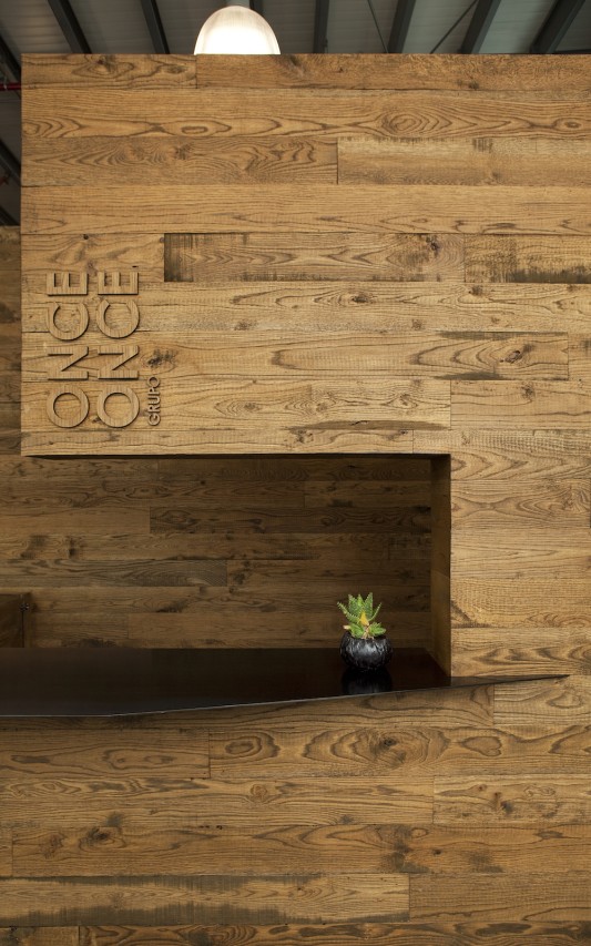 Defining the character of the project, the reception, framed by an imposing block of wood, welcomes you to Grupo Once Once.
