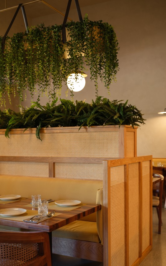 The booth partition breaks the open space to create more intimate sections while also accommodating refreshing flora.